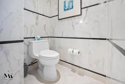 a bathroom with a white toilet and marble walls at FontaineBleau Resort Balcony w Ocean and City View in Miami Beach