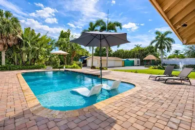 a swimming pool with two chairs and an umbrella at Villa Fiesta - Celebrate Dreams Create Memories in Southwest Ranches