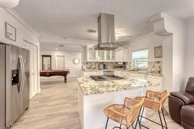 a kitchen with a counter and a living room with a piano at Mango Manor - Walk to Las Olas! in Fort Lauderdale