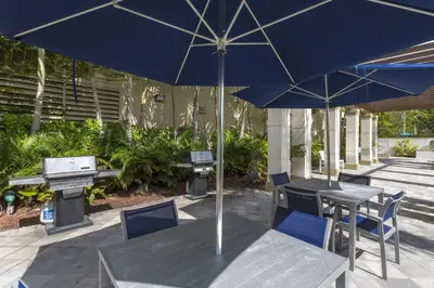a table and chairs with an umbrella on a patio at Coral Gables 2br w wd pool gym near shops MIA-83 in Miami