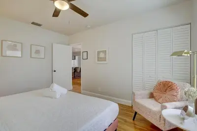 a white bedroom with a bed and a chair at Tranquil Poolside Bliss Pergola Deck Turf Yard in Fort Lauderdale