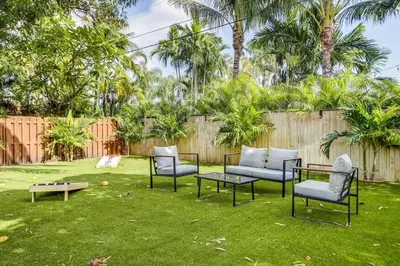 a yard with chairs and a table and a fence at Tranquil Poolside Bliss Pergola Deck Turf Yard in Fort Lauderdale