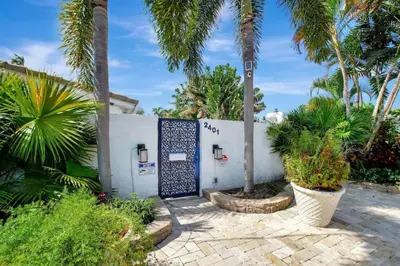 a white house with palm trees and a gate at Wilton on the water courtyard and Heated Pool in Fort Lauderdale