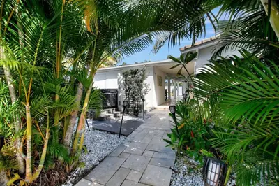 a garden with palm trees and a walkway at Wilton on the water courtyard and Heated Pool in Fort Lauderdale