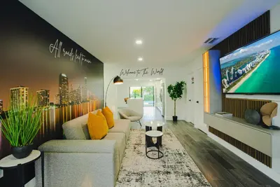 a living room with a couch and a large tv at The World's Mansion - Game Room, 9 Bedrooms, Htd Pool, Mini Golf, BBQ in Tamiami