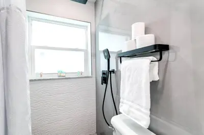 a bathroom with a toilet and a window and towels at Coral Way Studio in quiet area Fast Internet Shen 1 in Miami
