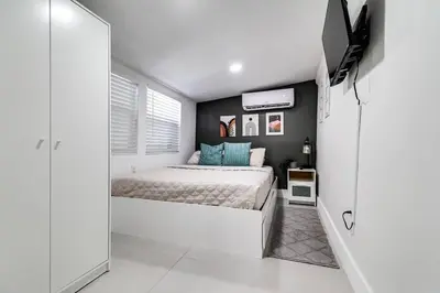 a white bedroom with a bed and a television at Miami studio apartment, Very centric, Fast Wi-Fi V4 in Miami