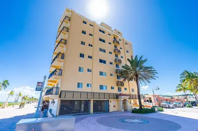 a tall building with a palm tree in front of it at Beach Front 1 Bedroom with Ocean View, Pool and Parking in Hollywood