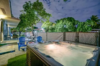 a hot tub in a backyard with two blue chairs at Wynwood Bungalow Hottub & Pking in Miami