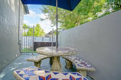 a table and benches with an umbrella on a patio at Wynwood Bungalow Hottub & Pking in Miami
