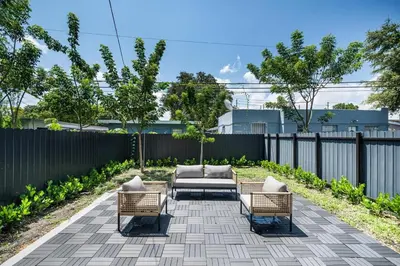 a patio with a couch and two chairs and a fence at 4 Bedroom Holiday Retreat BBQ Marketplace in Miami