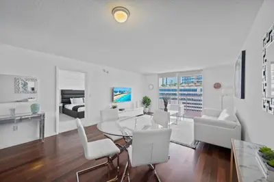 a living room with a glass table and white chairs at Well Located Unit with parking - Heart Of Brickell in Miami