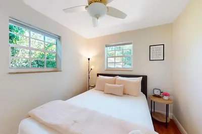 a bedroom with a white bed and two windows at Hallandale Hideaway in Hallandale Beach
