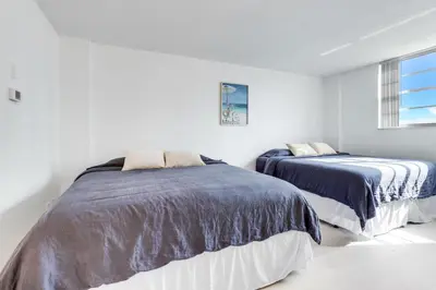 two beds in a bedroom with white walls at Spacious Family Escape with Pool & Beach Access in Sunny Isles Beach