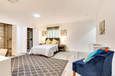 a white bedroom with a bed and a blue chair at Spacious and Serene Miami Home Walk to Metrorail! in Miami