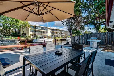 a wooden table with an umbrella on a patio at Citrus Isles Waterfront Home in Fort Lauderdale