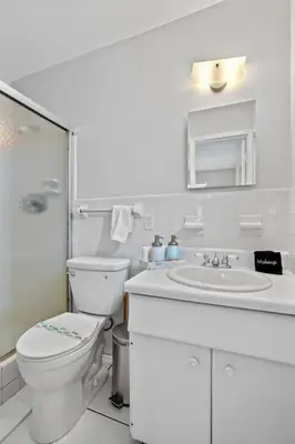 a white bathroom with a toilet and a sink at Citrus Isles Waterfront Home in Fort Lauderdale