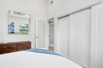 a white bedroom with a bed and a mirror at Breathtaking Pool Home and Backyard by Wilton Mnrs in Fort Lauderdale