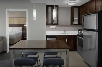 a kitchen with a table and chairs and a bed at Residence Inn by Marriott Fort Lauderdale Airport & Cruise Port in Dania Beach