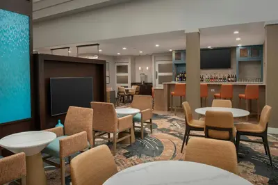 a room with tables and chairs and a bar at Residence Inn by Marriott Fort Lauderdale Airport & Cruise Port in Dania Beach
