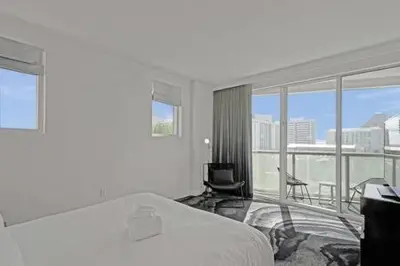 a white bedroom with a bed and a balcony at WVR Vacation Residences 709 in Fort Lauderdale