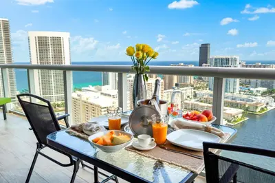a table with food and drinks on top of a balcony at Ocean Views - Pool & Gym - Pet Friendly - Close to Beach in Hallandale Beach