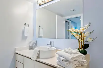 a white bathroom with a sink and a mirror at Ocean Views - Pool & Gym - Pet Friendly - Close to Beach in Hallandale Beach