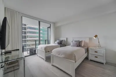 a bedroom with two beds and a tv and a window at Unwind in Your Amazing City View Apartment in Miami