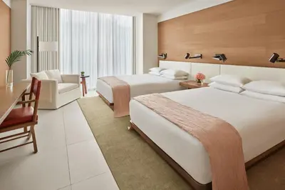 a hotel room with two beds and a chair at The Miami Beach EDITION in Miami Beach