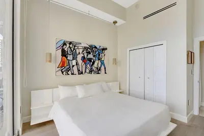 a bedroom with a white bed and a painting on the wall at Brickell Oasis 5BR Free Parking Pool Gym and More in Miami