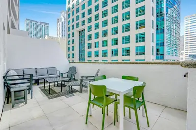 a table and chairs on a balcony with a building at Brickell Oasis 5BR Free Parking Pool Gym and More in Miami