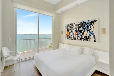 a bedroom with a large white bed and a large window at Brickell Oasis 5BR Free Parking Pool Gym and More in Miami