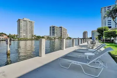 a row of chairs sitting next to a body of water at Vistamar Waterfront Beach Abode -Walk to the Beach in Fort Lauderdale
