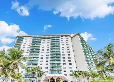 a tall white building with palm trees in front of it at Beachside Bliss: 1BR Retreat Amenities in Sunny Isles Beach