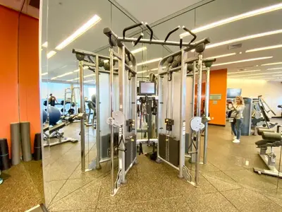 a gym with cardio equipment and a woman in the background at 5th Floor Luxury Suite at Trump Int Resort in Sunny Isles Beach
