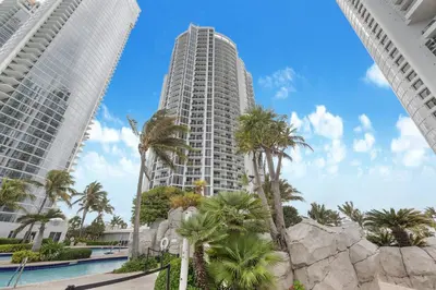 a tall white building with palm trees in front of it at 5th Floor Luxury Suite at Trump Int Resort in Sunny Isles Beach