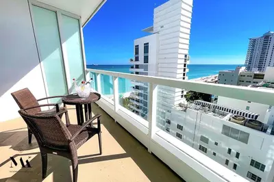 a balcony with two chairs and a table and the ocean at FontaineBleau Resort Balcony w Ocean + Bay View in Miami Beach
