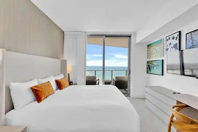 a bedroom with a large white bed with orange pillows at Beachfront Escape Pool Gym Stunning Views 30th floor in Hallandale Beach