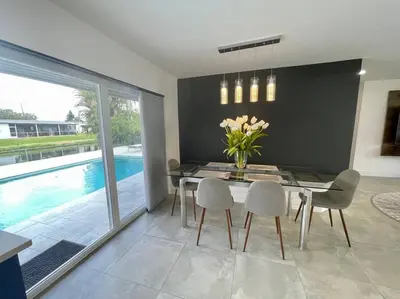 a dining room with a table and chairs and a pool at Modern pool home on the lake near Hardrock FLL airport in Davie