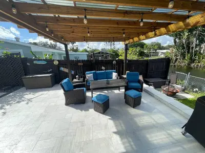 a patio with a table and chairs under a pergola at Modern pool home on the lake near Hardrock FLL airport in Davie