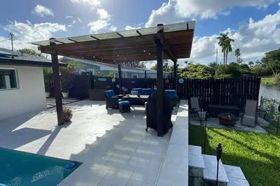 a patio with a wooden pergola and a pool at Modern pool home on the lake near Hardrock FLL airport in Davie