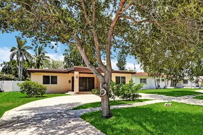 a house with a tree in front of a driveway at Luxury 4BR & 4BA Villa Heated Pool Minutes To Beach in Hollywood