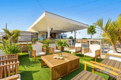 a patio with wooden tables and chairs on the grass at New Studio - Hollywood Beach Bliss for 2 in Hollywood