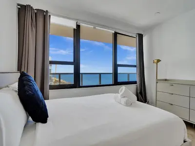 a bedroom with a white bed and large windows at Ocean Front Penthouse 2BD 2 Balconies PH-2 in Miami Beach