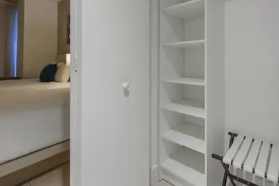 a closet with white shelves next to a bed at Beachside Condo with a Mesmerizing Ocean View in Hollywood