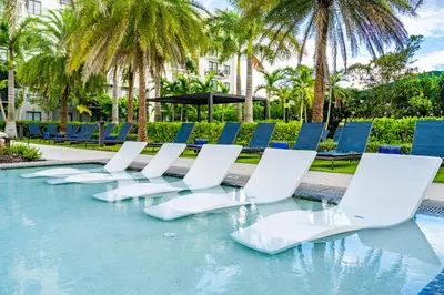 a row of lounge chairs in a swimming pool at Modern 1 Bedroom In The Heart Of Downtown Doral in Hialeah Gardens