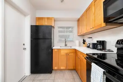 a kitchen with a black refrigerator and wooden cabinets at Bayshore Breeze Free Parking 1 in Fort Lauderdale