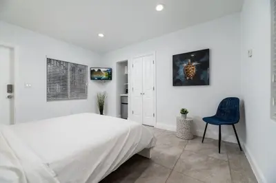a white bedroom with a bed and a blue chair at Bayshore Breeze 2 in Fort Lauderdale