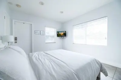 a white bedroom with a white bed and two windows at Bayshore Breeze 4 in Fort Lauderdale
