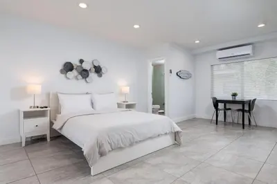 a white bedroom with a large bed and a table at Bayshore Breeze Free Parking 7 in Fort Lauderdale